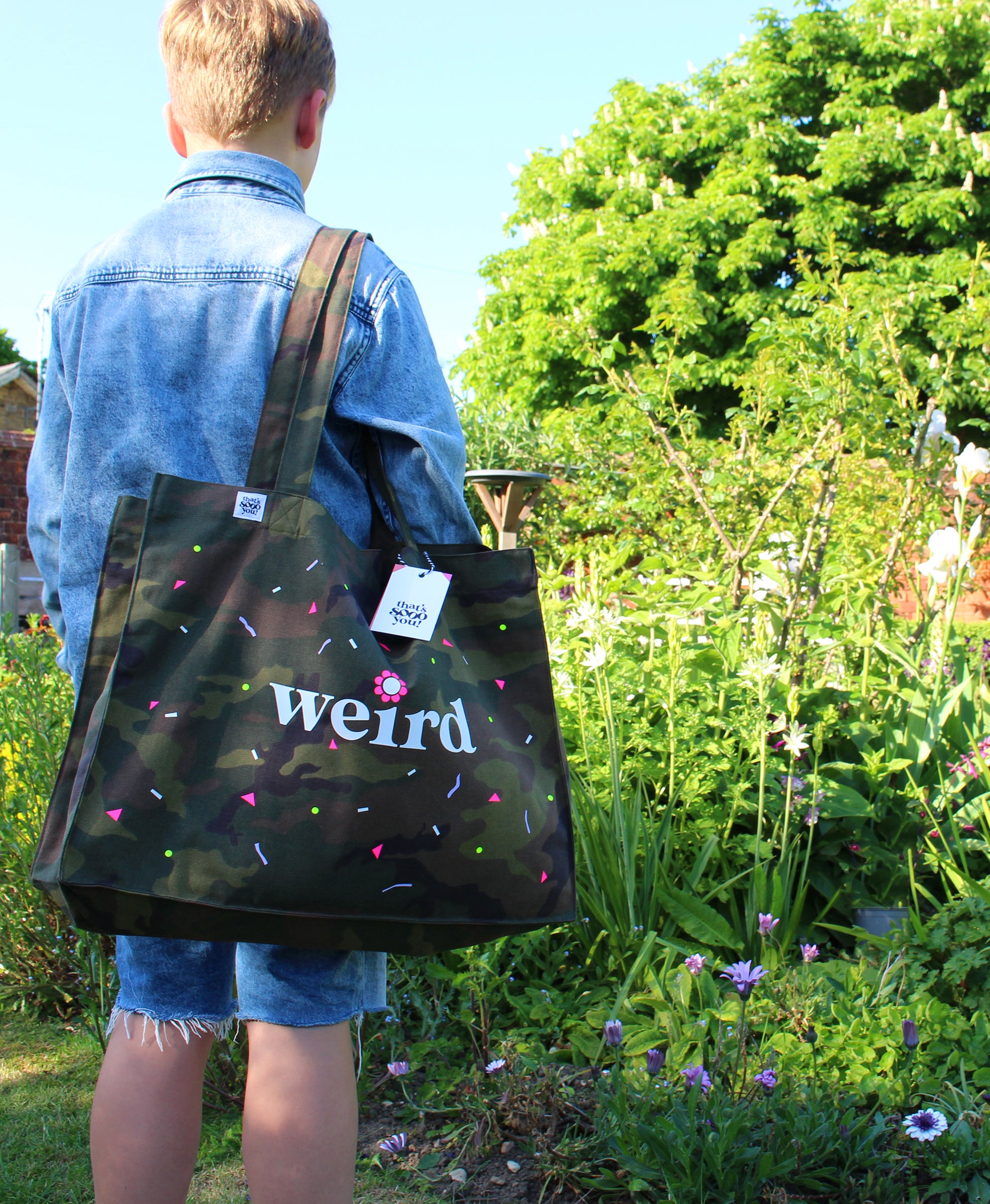 Teen boy in denim holding That's Sooo You Weird custom XL tote bag, shopper, camo, white, pink, lilac, yellow, neon